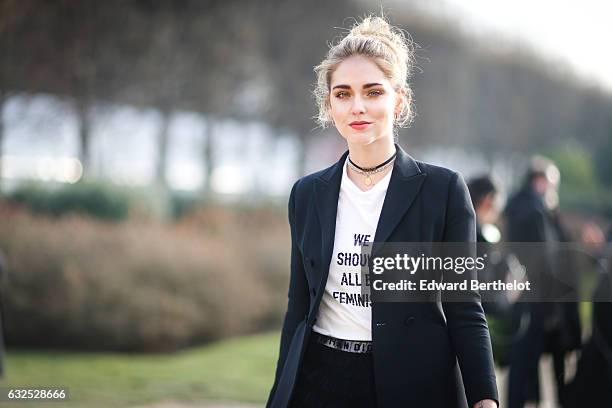 Chiara Ferragni wears sunglasses, a white t-shirt with the inscriptions " We should all be Feminists", a black meshed dress, black heels, and attends...