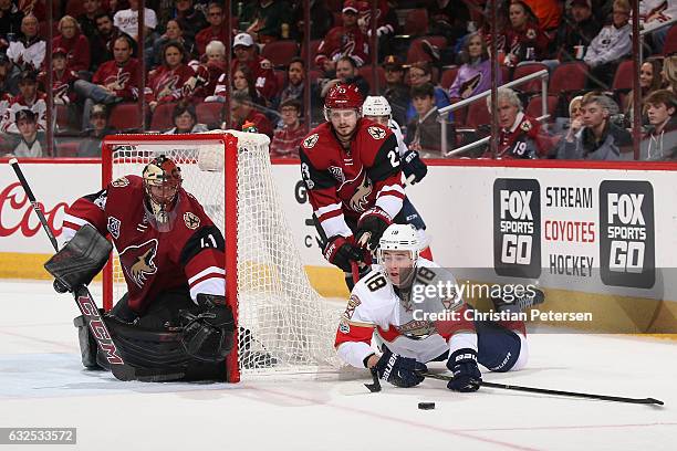 Reilly Smith of the Florida Panthers attempts to center the puck ahead of goaltender Mike Smith and Oliver Ekman-Larsson of the Arizona Coyotes...