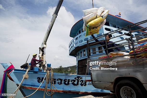 Worker on a ferry uses a crane to move bags of rice on to the back of a pickup truck in Koh Phangan, Surat Thani, Thailand, on Wednesday, Jan. 18,...