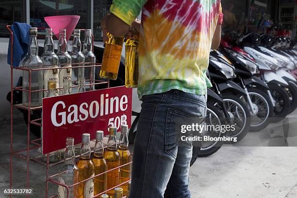 Man picks up re-used whiskey bottles containing gasoline from a rack outside a store in Koh Phangan, Surat Thani, Thailand, on Wednesday, Jan. 18,...