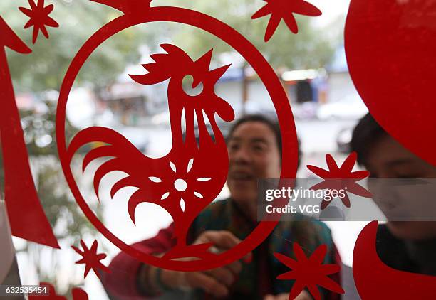 People post a paper cutting of rooster on the window on January 23, 2017 in Wenzhou, Zhejiang Province of China. To welcome the Year of Rooster,...