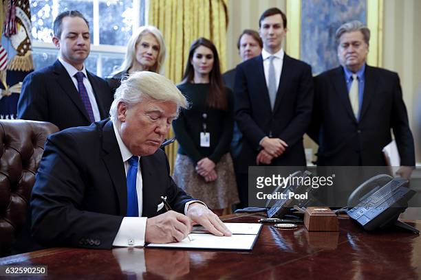 President Donald Trump signs one of five executive orders related to the oil pipeline industry in the Oval Office of the White House January 24, 2017...