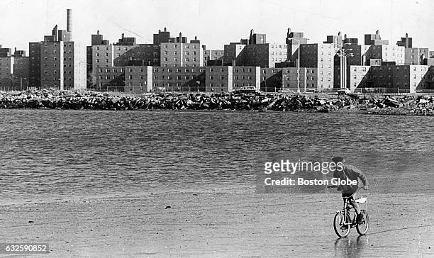 Michael Peterson of Dorchester, rides his bicycle on Carson Beach in Boston on April 25, 1967. The Columbia Point housing project is in the...