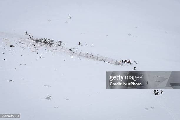 Rescuers work near the wreck of an helicopter following a crash that killed six people, on January 24, 2017 in the mountains near the ski resort of...