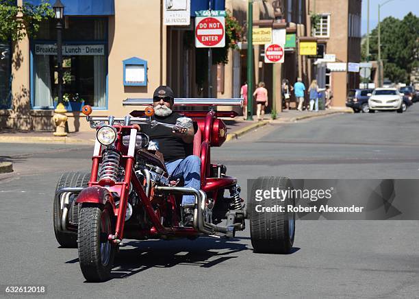 Man rides his customized Harley-Davidson trike motorcycle along a street in Santa Fe, New Mexico.