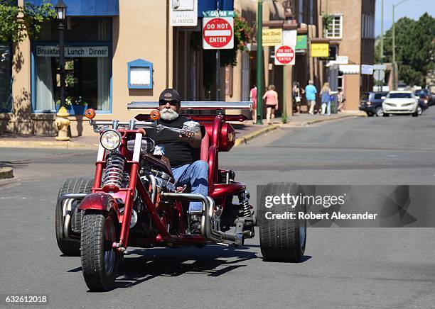 Man rides his customized Harley-Davidson trike motorcycle along a street in Santa Fe, New Mexico.