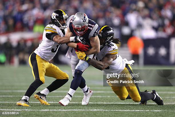 Ross Cockrell and Bud Dupree of the Pittsburgh Steelers attempt to tackle Julian Edelman of the New England Patriots in the AFC Championship Game at...