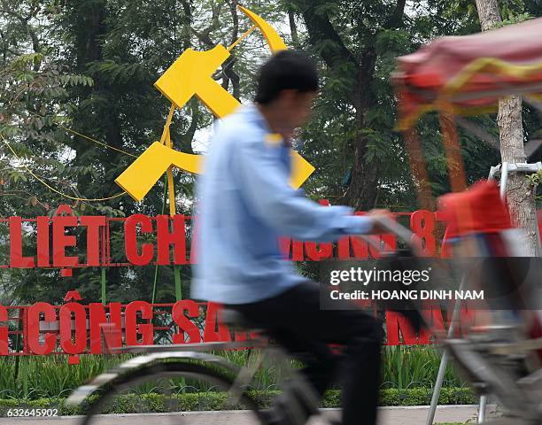 Cyclo rider passes a communist sign installed to mark the upcoming 87th anniversary of the ruling communist party of Vietnam in downtown Hanoi on...