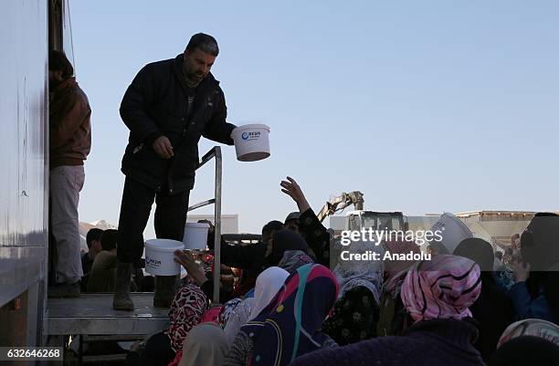 Man distributes meal as women wait in a queue with their plastic and iron buckets at a tent city built up for the families coming from Aleppo, in...