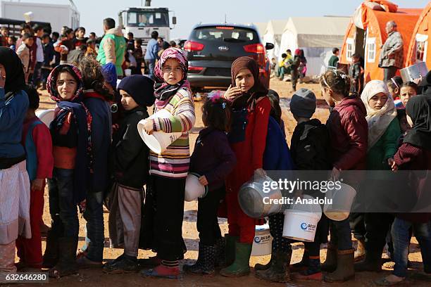 Children wait in a queue with their plastic and iron buckets to get meal at a tent city built up for the families coming from Aleppo, in northern...