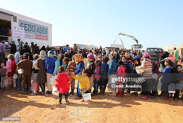 Children wait in a queue with their plastic and iron buckets to get meal at a tent city built up for the families coming from Aleppo, in northern...