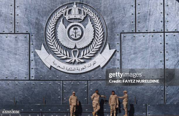 Army officers stand under the Saudi Air Force logo during a ceremony marking the 50th anniversary of the creation of the King Faisal Air Academy at...