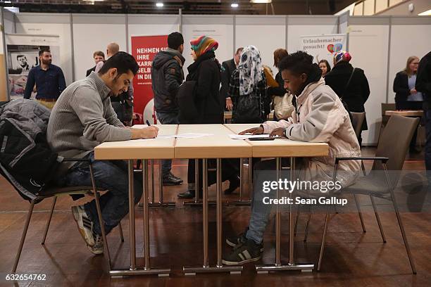 Two young men, who said they did not mind being photographed, fill out job applications at the second annual jobs fair for refugees and migrants at...