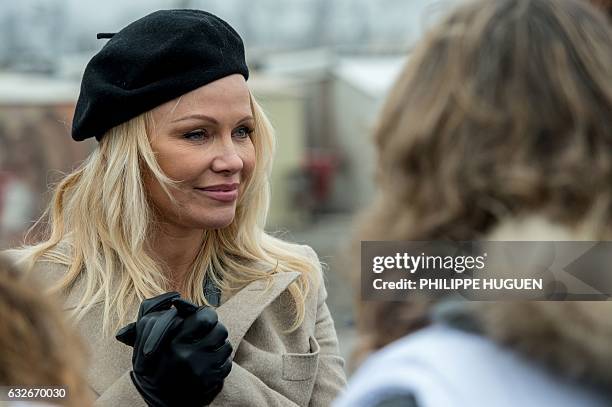 Canadian actress Pamela Anderson speaks with personnel in the migrant and refugee camp of Grande-Synthe, northern France, on January 25 during a...