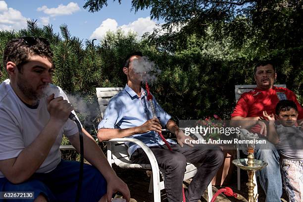Badi Dabjan, a volunteer in the Syrian community and asylum seeker, smokes hookah with Nedal Al Hayek and Thaer Hoshan, both refugees from Daraa,...