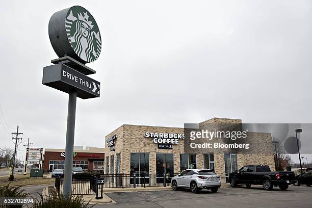 Vehicles sit parked outside of a Starbucks Corp. Coffee shop in Peoria, Illinois, U.S., on Wednesday, Jan. 25, 2017. Starbucks Corp. Is expected to...