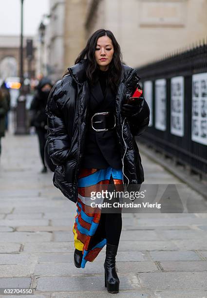Tina Leung wearing a black down feather jacket, striped skirt with eye print outside Jean Paul Gaultier on January 25, 2017 in Paris, Canada.