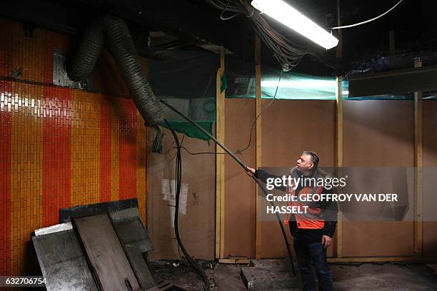 Construction worker points to a pipe containing potential asbestos during the renovation of the Chatelet Les Halles Metro station in central Paris,...