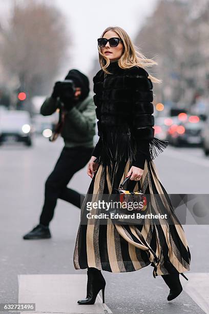 Olivia Palermo wears black sunglasses, a black fur coat, a striped dress, and black heels, outside the Elie Saab show, during Paris Fashion Week...