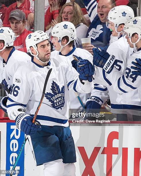 Roman Polak of the Toronto Maple Leafs pounds gloves with teammates on the bench following his second period goal during an NHL game against the...