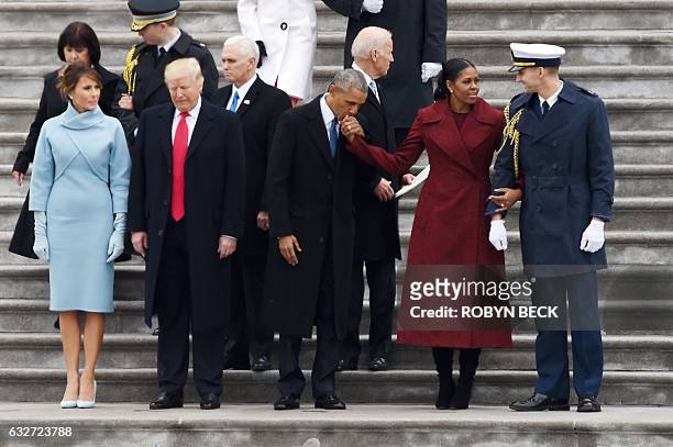 Former President Barack Obama kisses the hand of former First Lady Michelle Obama beside US President Donald Trump and First Lady Melania Trump...