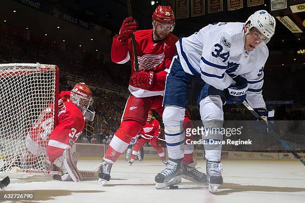 Auston Matthews of the Toronto Maple Leafs battles for the puck with Mike Green of the Detroit Red Wings in front of goaltender Petr Mrazek of the...