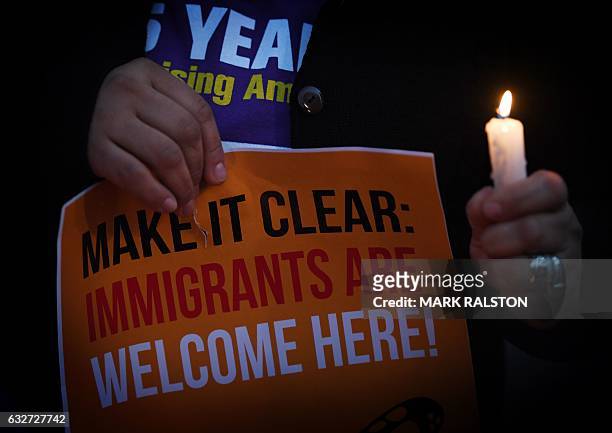 Migrant rights groups hold candles during a vigil to protest against US President Donald Trump's new crackdown on "sanctuary cities", outside the...