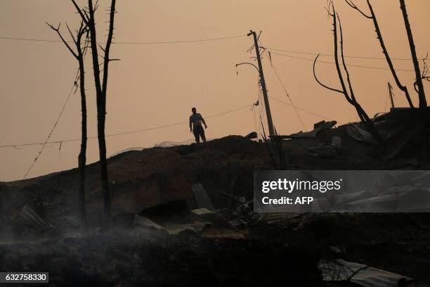 Man stands amid the remains of a burnt down house after a forest fire devastated Santa Olga, 240 kilometres south of Santiago, on January 26, 2017. -...