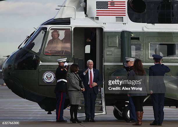 Vice President Mike Pence salutes as he gets off the Marine Two for boarding the Air Force Two with his wife Karen January 26, 2017 at Joint Base...