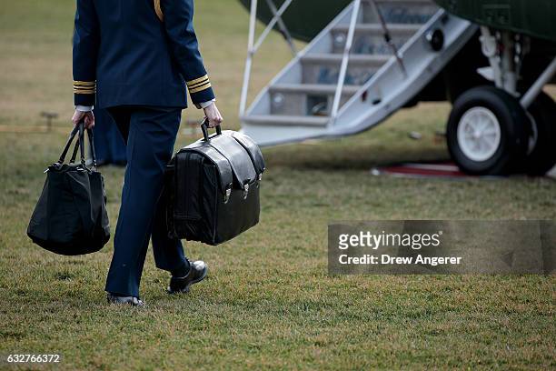 Military aide carries the alleged 'football,' a case with the launch codes for nuclear weapons, toward Marine One as U.S. President Donald Trump...