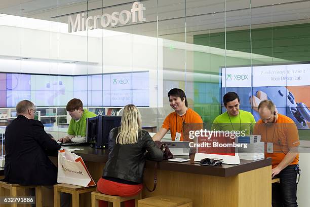 Employees assist customers at a store location in Bellevue, Washington, U.S., on Thursday, Jan. 26, 2017. Microsoft Corp.'s second-quarter sales and...