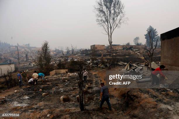 People work to clean up the debris after a forest fire devastated Santa Olga, 240 kilometres south of Santiago, on January 26, 2017. Six people --...