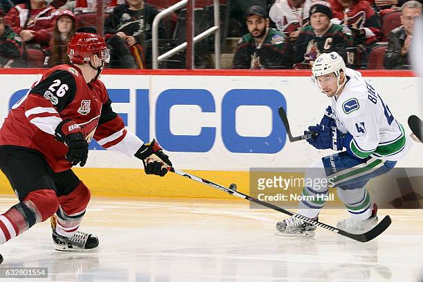 Michael Stone of the Arizona Coyotes and Sven Baertschi of the Vancouver Canucks skate for a loose puck during the second period at Gila River Arena...