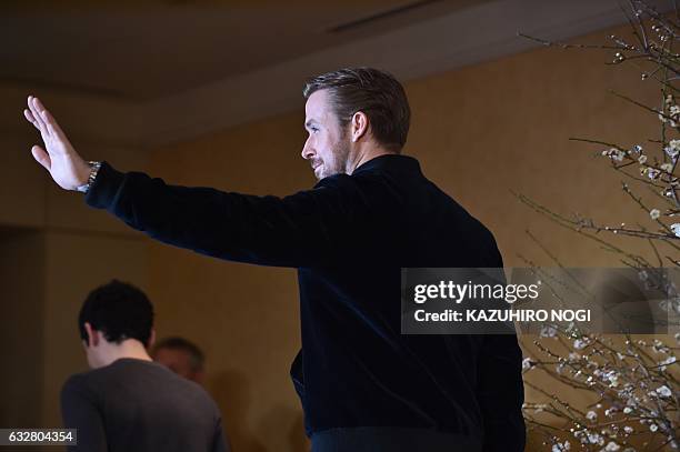 Canadian actor Ryan Gosling waves to the media as he leaves with US film director Damien Chazelle after a press conference for their film "La La...