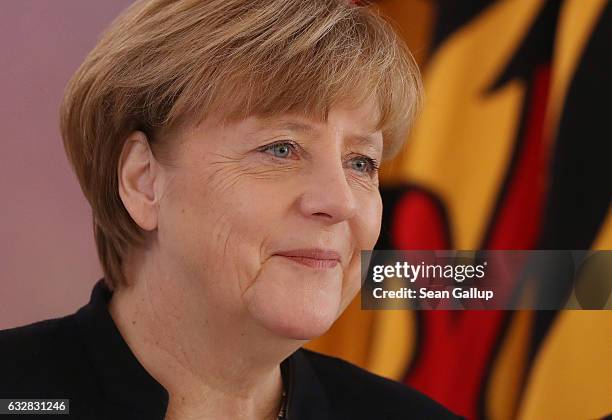 German Chancellor Angela Merkel stands next to a flag with the German Federal Eagle as she attends a ceremony in which President Joachim Gauck...