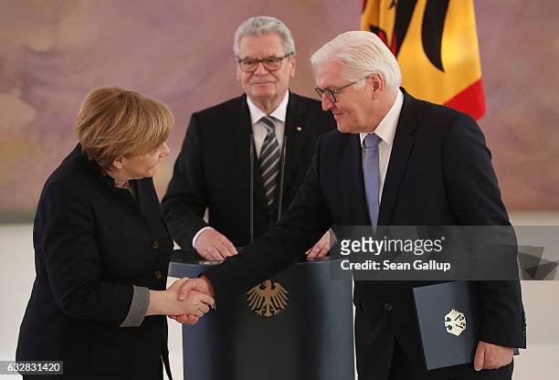 German Chancellor Angela Merkel shakes hands with outgoing Foreign Minister Frank-Walter Steinmeier as President Joachim Gauck looks on during a...