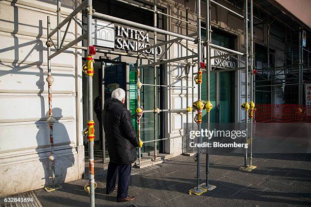 Pedestrian waits to enter an Intesa Sanpaolo SpA bank branch, surrounded by scaffolding, in Rome, Italy, on Friday, Jan. 27, 2017. Intesa Chief...