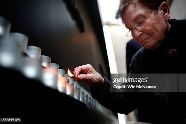 Holocaust survivor Josiane Traum lights a memorial candle during an International Holocaust Remembrance Day Commemoration at the United States...