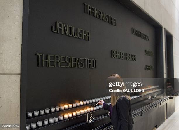 Woman lights a Memorial Candle during an International Holocaust Remembrance Day Commemoration at the United States Holocaust Memorial Museum in...