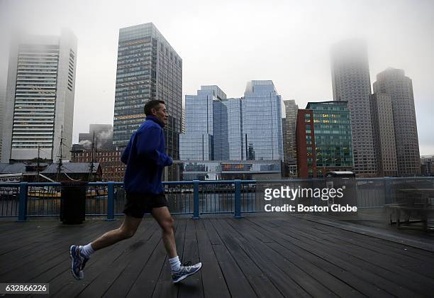 Man jogs along the Harborwalk in Fort Point channel as fog obscures the skyline in Boston on Mar. 17, 2016.