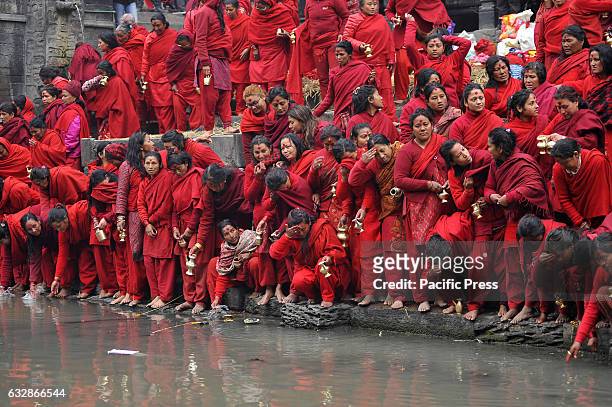 Nepalese Hindu Devotees lining to take holy water from Bagmati River at Pashupathnath Temple, Kathmandu during Madhav Narayan Festival or Swasthani...