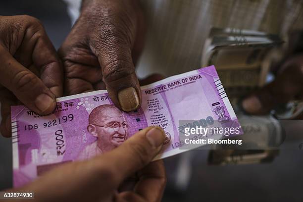 Men hold a two thousand Indian rupee banknote for a photograph in Mumbai, India, on Friday, Jan. 27, 2017. While economists urge more investment in...