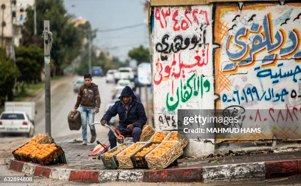 Palestinian fruit-seller lights a fire to warm up after the rain in the Gaza City on January 28, 2017.