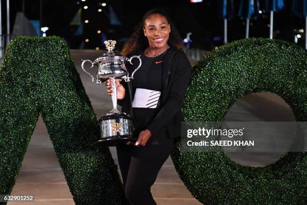 Serena Williams of the US poses with the championship trophy after her victory against Venus Williams of the US in the women's singles final on day...