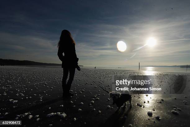 Young woman enjoys the sun walking her dog on Lake Ammersee on January 28, 2017 in Stegen am Ammersee, Germany. After an unusual cold winter period...