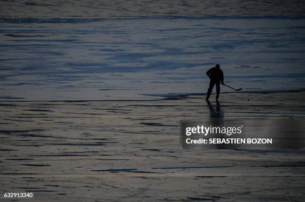 Man plays ice hockey on the frozen lake of Gerardmer, eastern France, on January 28, 2017.