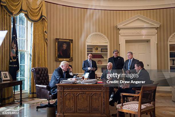 President Donald Trump speaks on the phone with Russian President Vladimir Putin in the Oval Office of the White House, January 28, 2017 in...