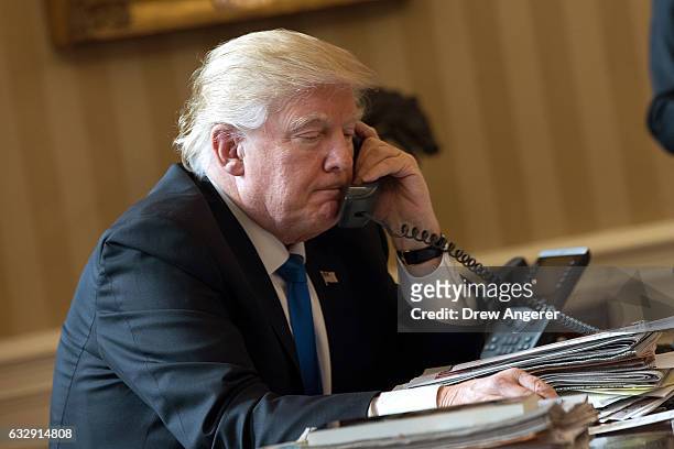 President Donald Trump speaks on the phone with Russian President Vladimir Putin in the Oval Office of the White House, January 28, 2017 in...