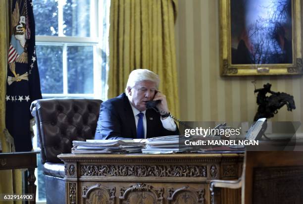 President Donald Trump speaks on the phone with Russia's President Vladimir Putin from the Oval Office of the White House on January 28 in...