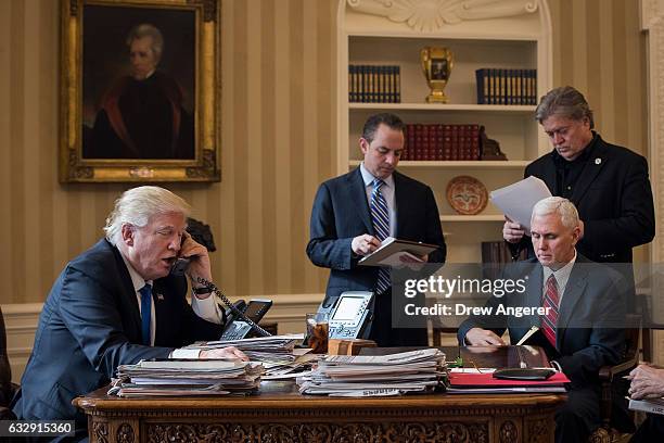 President Donald Trump speaks on the phone with Russian President Vladimir Putin in the Oval Office of the White House, January 28, 2017 in...